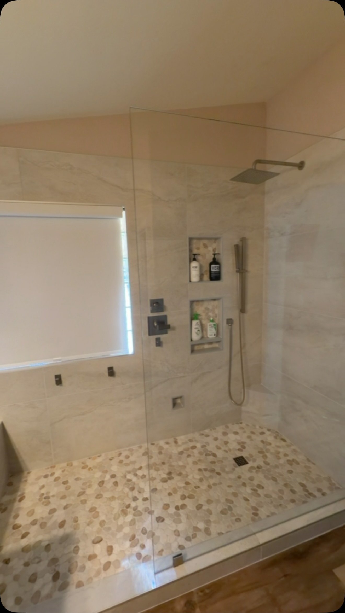 Custom walk-in shower with pebble floor and tile niches
